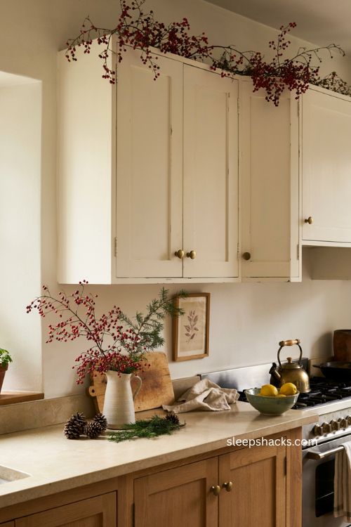 Red berry branches above white kitchen cabinets for classic Christmas decor 