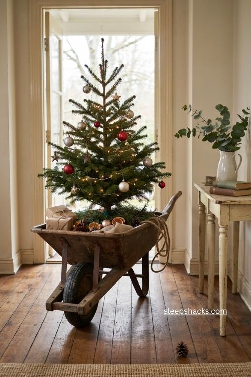 Rustic wheelbarrow Christmas tree stand with greenery vintage ornaments and farmhouse holiday decor 