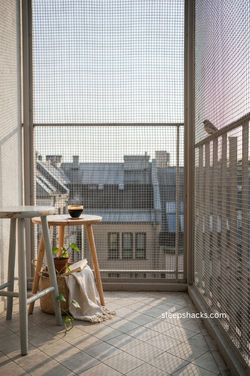 See through mesh enclosure for small balcony with simple stool and side table