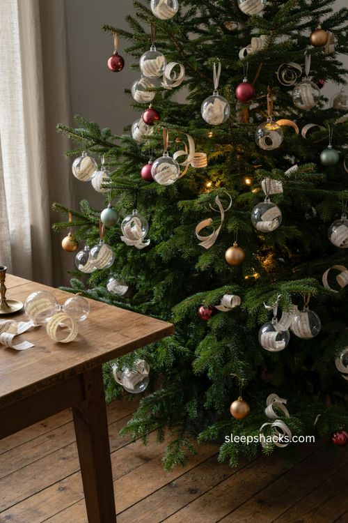 Sheet music sphere ornaments with curled vintage paper strips inside clear christmas balls and cozy tree decor 