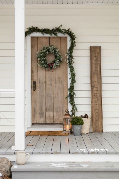Small front porch Christmas decor with leaning seasonal sign and farmhouse entryway 