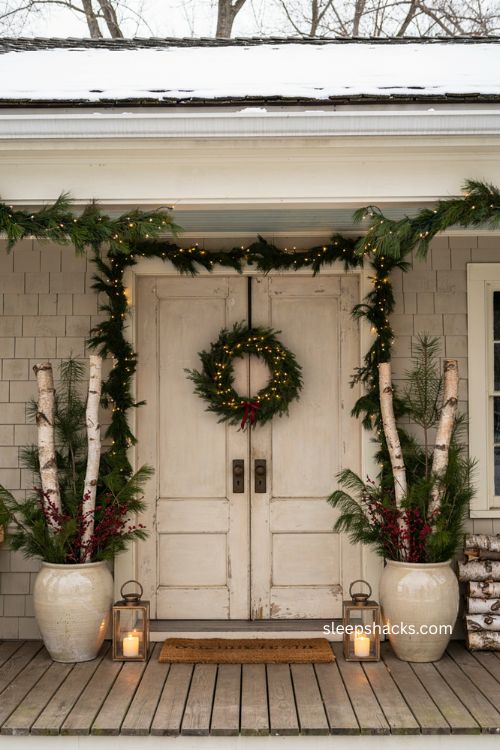 Small front porch Christmas decor with symmetrical twin planters pine greenery and birch logs 