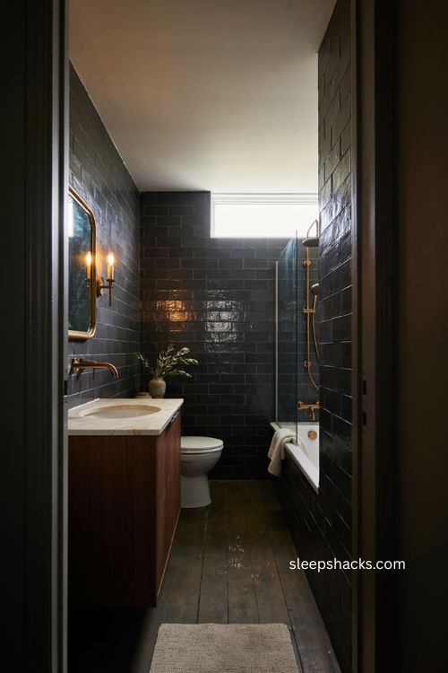 Small full bathroom with dark glossy walls brass fixtures and dramatic cozy style 