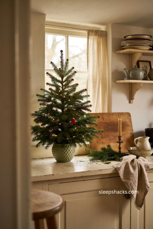 Small lit Christmas tree on cozy kitchen counter with woven container 