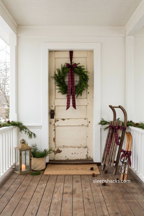 Small porch Christmas decor with matching ribbon on sled skis and wreath 
