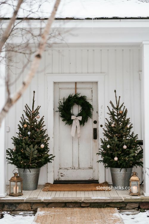 Small porch Christmas decor with twin mini trees beside the front door 