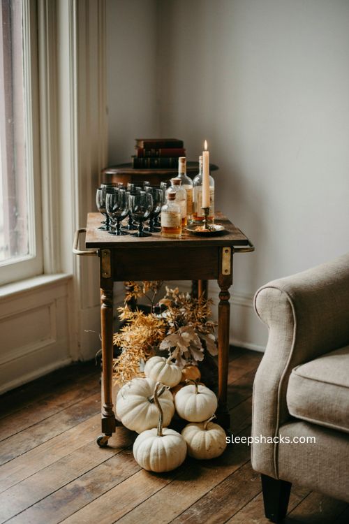 Spooky Halloween bar cart with black glassware white pumpkins and dried foliage 