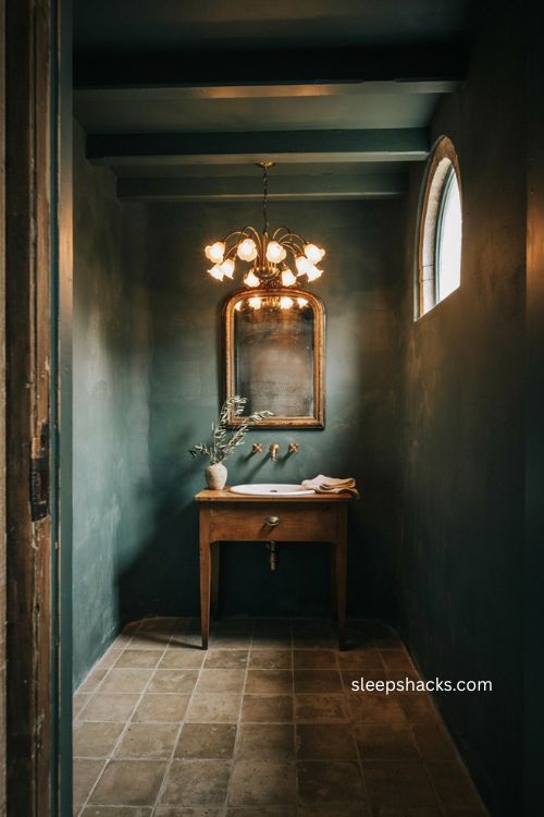 Statement lighting moody bathroom with brass pendant dark walls vintage vanity and warm glowing contrast 