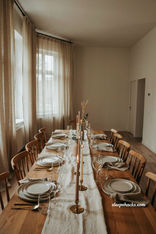 Taper candle Thanksgiving table centerpiece with warm glowing candles and neutral linen decor
