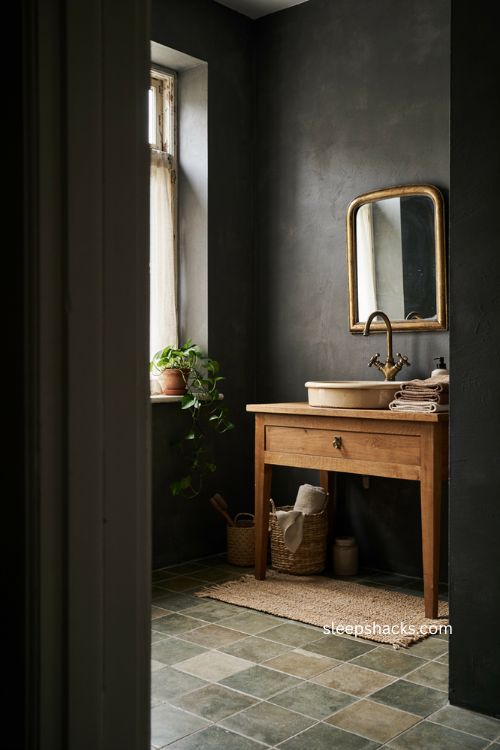 Textured moody bathroom with dark walls woven baskets tiled floor linen towels and warm natural details 