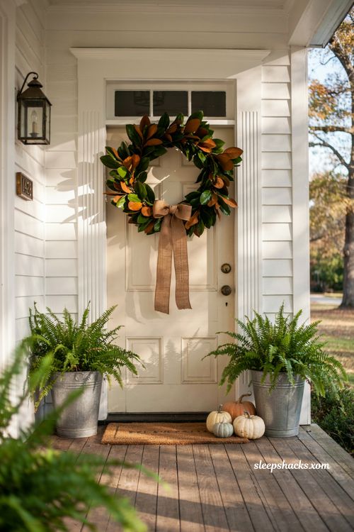 Thanksgiving front porch decor ideas with magnolia leaves evergreen garland and ferns
