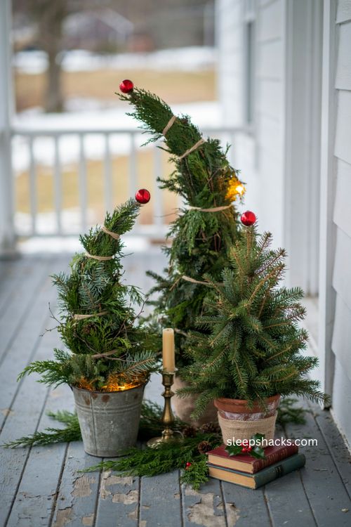 Trio of diy grinch christmas trees in graduating sizes with red ornaments on porch