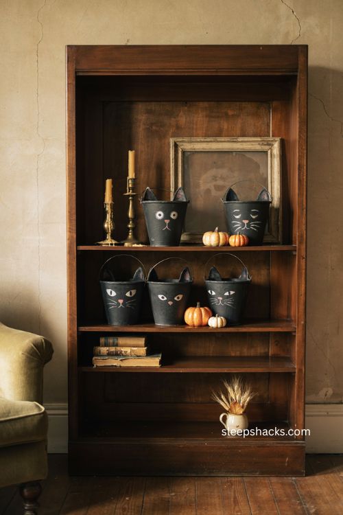 Vintage cat head buckets on a bookshelf with retro Halloween decor 