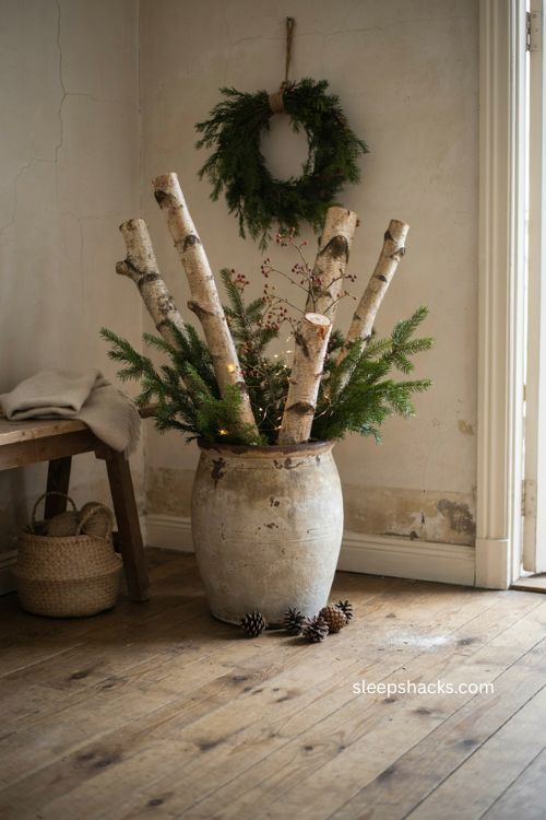 Warm Christmas decor with birch logs evergreen clippings and rustic crock arrangement 