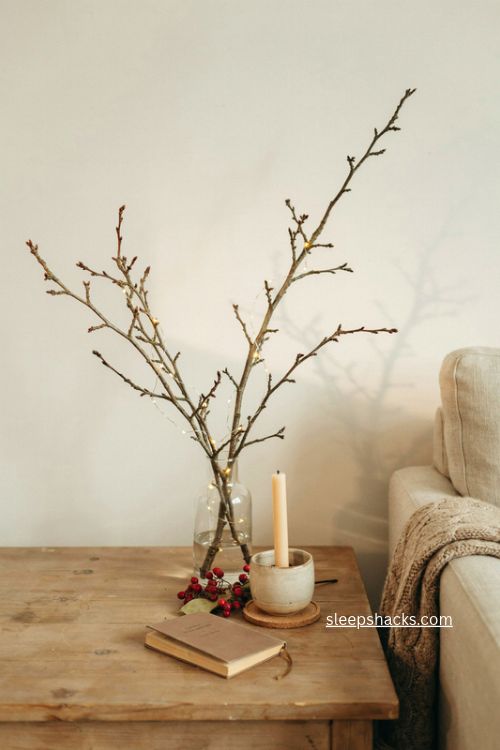 Winter berry christmas end table decor with lit branches and narrow glass vase 