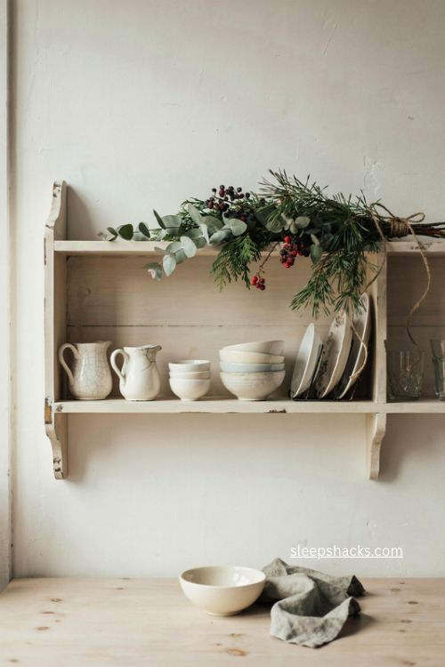christmas greenery swag over cottage kitchen dish shelf with vintage ceramics 
