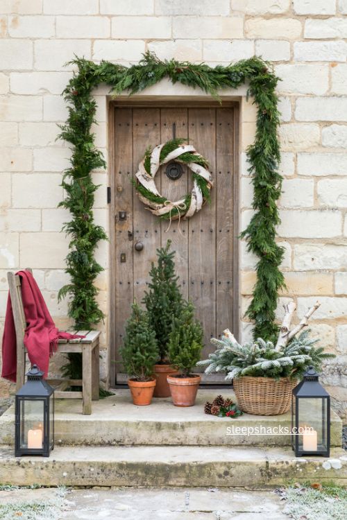 cozy cottage christmas front stoop with cypress garland birch wreath and red throw 