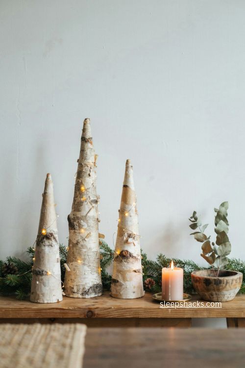 lit cone trees and birch bark christmas console table decor with evergreen garland 
