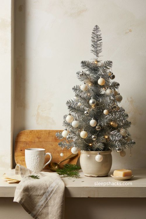 mini silver tabletop Christmas tree with tiny ornaments on a cozy kitchen counter 