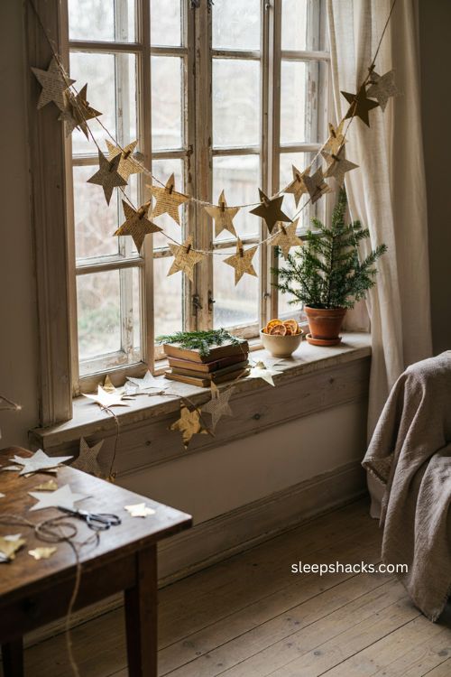 paper star Christmas garland with old book pages and gold stars by a window 