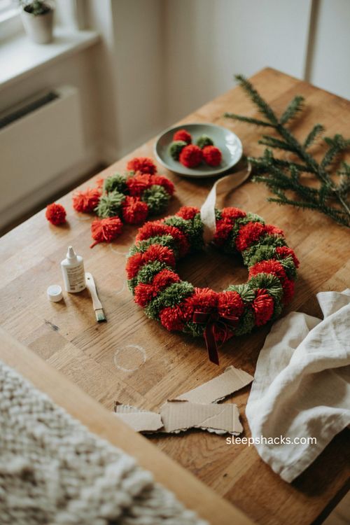 pom pom christmas wreath craft for toddlers with red and green pom poms cardboard ring and ribbon 