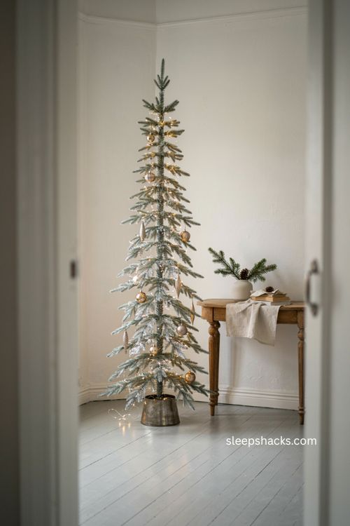 slim silver pencil Christmas tree with statement ornaments in a small entryway 