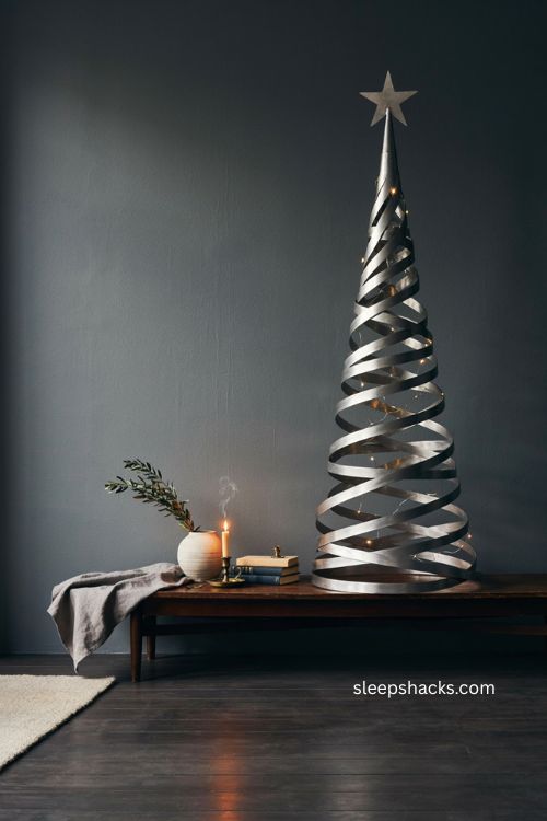 spiral silver Christmas tree with geometric design against a dark wall 