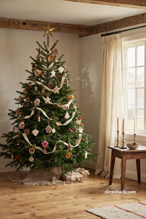A warm gingerbread themed christmas tree decorated with cozy rustic ornaments in a sunlit cottage living room