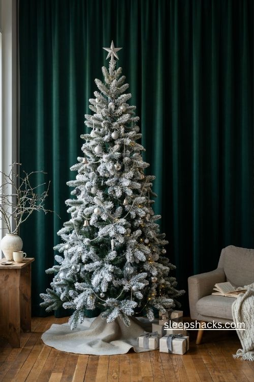 All white flocked pencil christmas tree with clear glass ornaments and silver bells