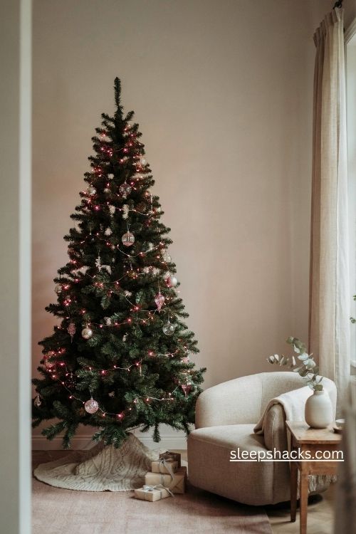 Black christmas tree glowing with soft pink and warm white lights and clear glass ornaments