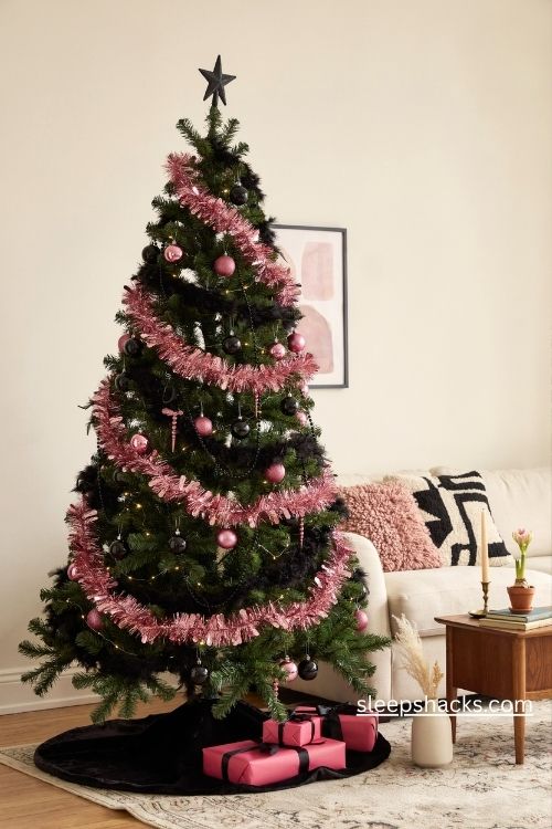Black christmas tree with pink tinsel garlands glossy ornaments and retro holiday party decor