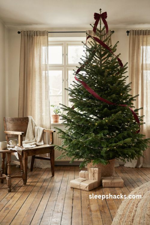 Burgundy ribbon wrapped Christmas tree with a matching bow and simple elegant decor