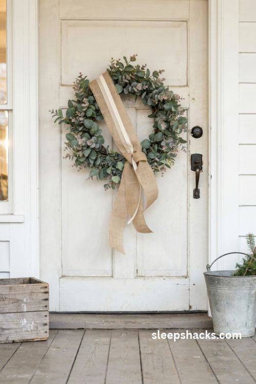 Burlap sash on a eucalyptus farmhouse Christmas wreath with cream ribbon and rustic wooden accents