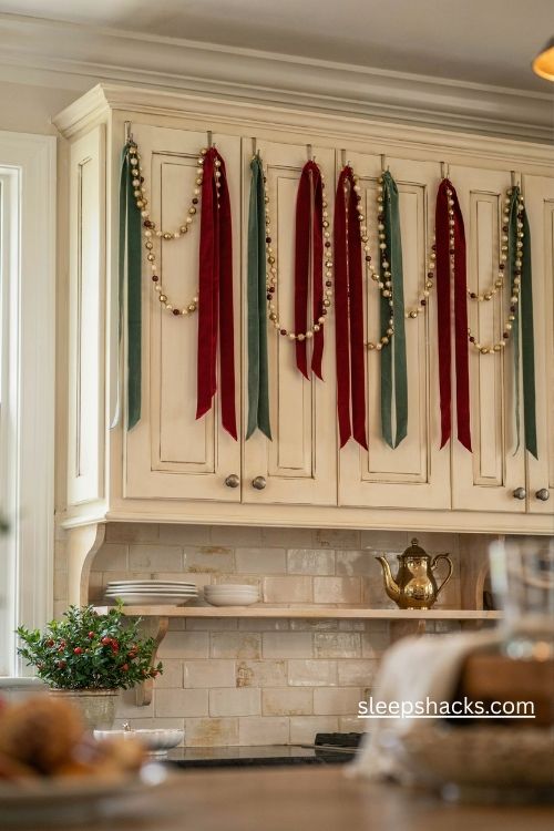 Cascading velvet christmas ribbons and pearl gold bead garlands on cream kitchen cabinet crowns