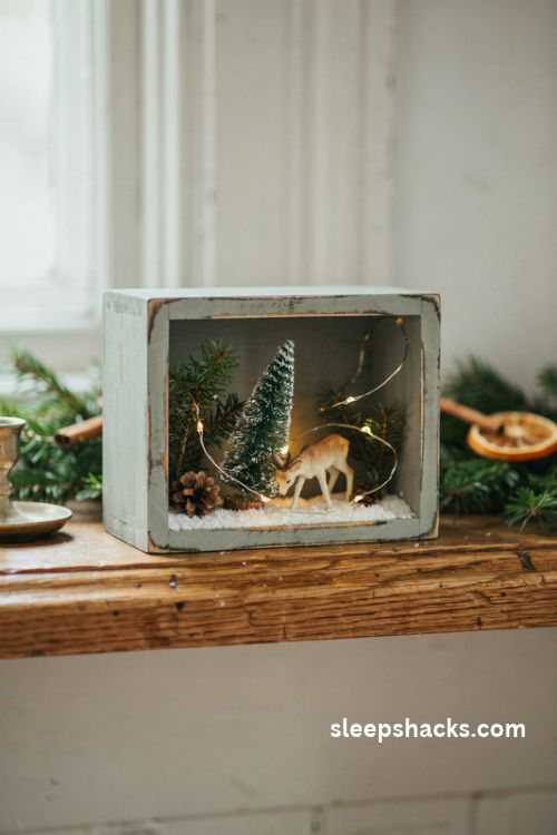 Christmas diorama ideas with a tiny deer, bottle brush tree, and glowing fairy lights in a rustic wooden box