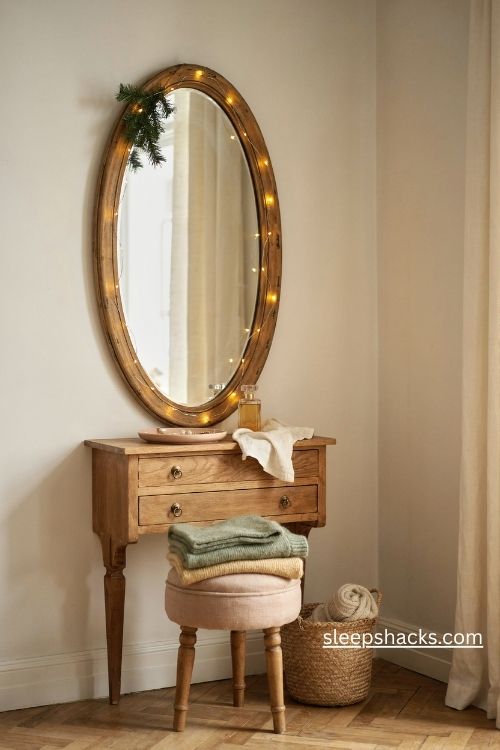 Christmas fairy lights wrapped around a vintage bedroom mirror with soft golden reflections and a touch of greenery
