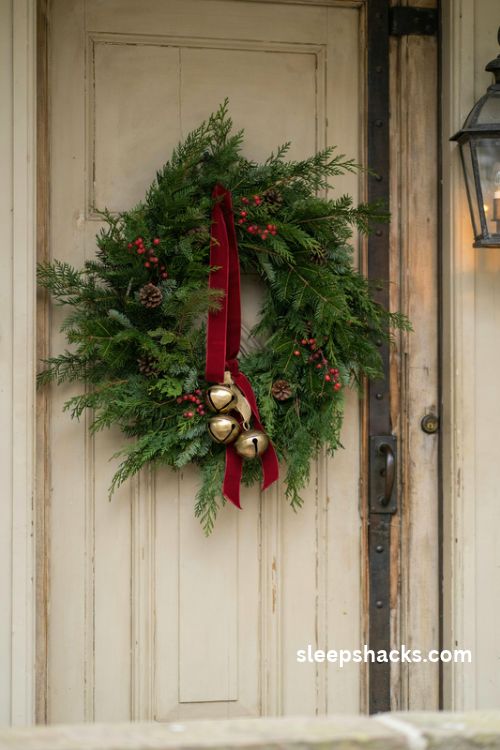 Christmas wreath sash with antique gold jingle bells and red velvet ribbon on a rustic front door