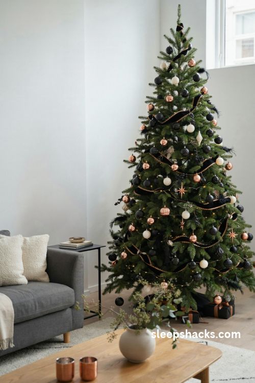 Copper and matte black christmas tree with modern ornaments and elegant white walls