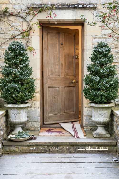 Cottage Christmas front porch with boxwood trees in stone urns and classic holiday decor 