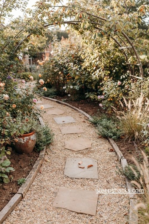 Curved gravel garden path with natural stepping stones and lush cottage garden plants