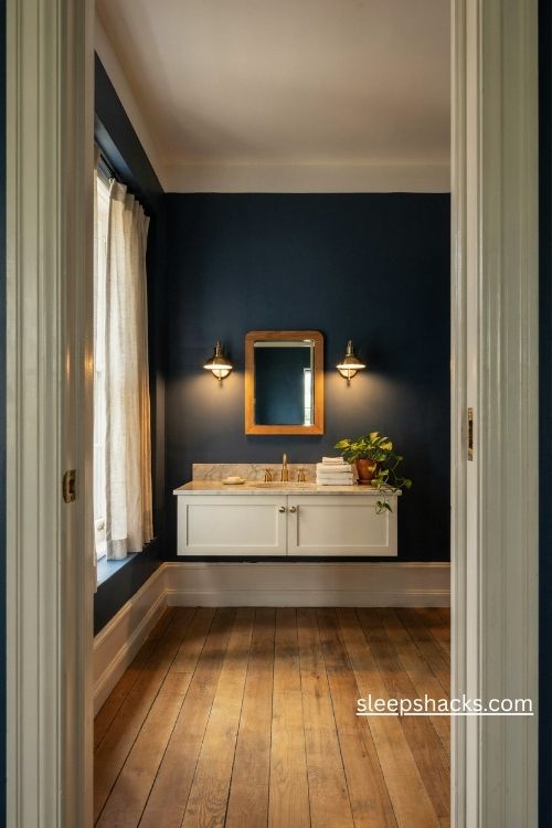 Deep navy bathroom walls with white trim brushed gold hardware and warm wood mirror