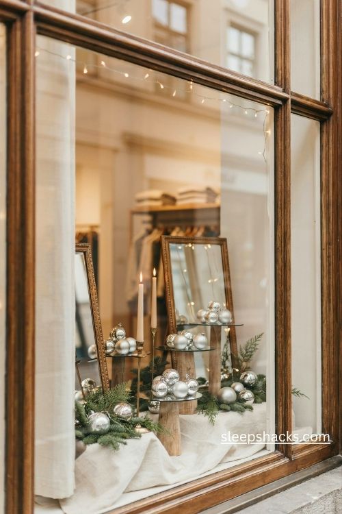 Elegant christmas storefront display with mirrored trays silver ornaments gold accents and warm reflected lights