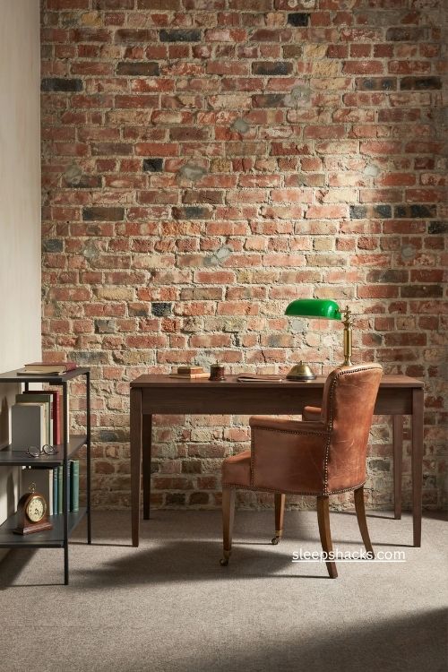 Exposed brick accent wall with dark wood desk in a masculine office