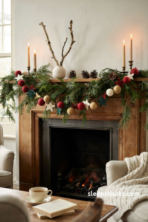 Felt Christmas garland mixed with fresh pine greenery red felt berries and ivory stars on a cozy mantel