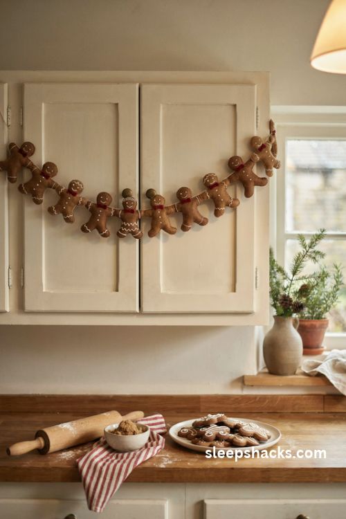 Felt gingerbread man Christmas garland with white stitched icing and red bow ties on a cozy kitchen cabinet