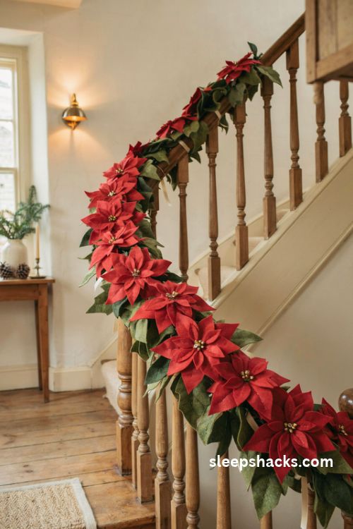 Felt poinsettia Christmas garland with layered red flowers and green leaves decorating a cozy wooden staircase