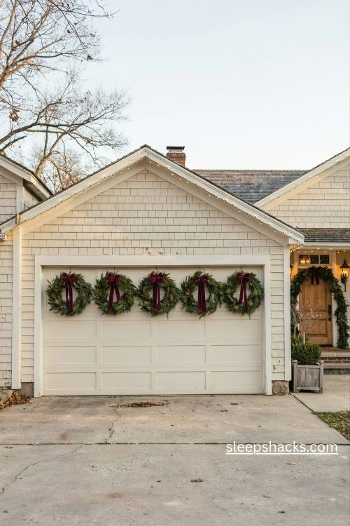 Garage door decorated with matching evergreen christmas wreaths and red ribbon bows