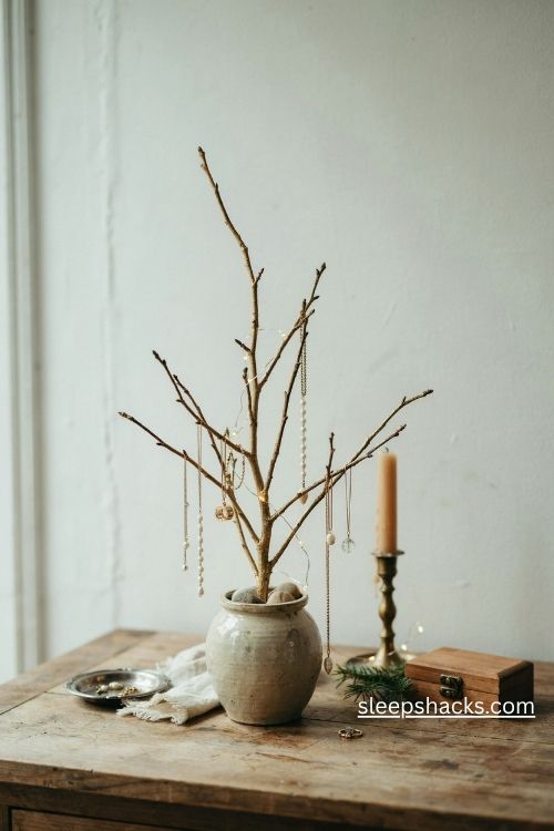 Gold branch jewelry stand with hanging pearl necklaces bracelets and subtle christmas decorations