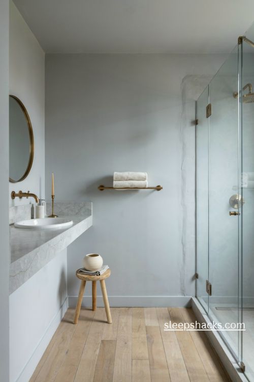 Grey bathroom with warm brushed brass fixtures and elegant stone surfaces 