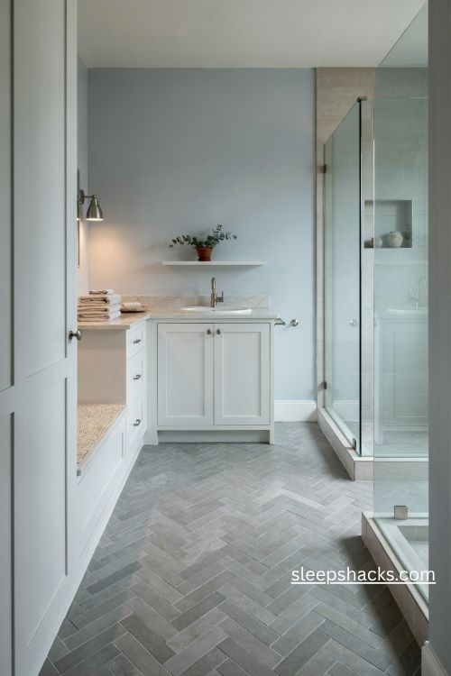 Grey herringbone bathroom floor with white vanity and soft neutral decor
